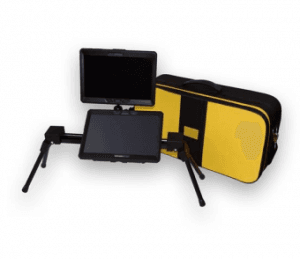 Na zdjęciu widoczny jest przenośny powiększalnik dla osób słabowidzących, składający się z dwóch ekranów zamocowanych na regulowanych ramionach oraz stabilnej podstawy. Ekrany są ustawione na statywach, co umożliwia dopasowanie ich wysokości i kąta nachylenia. Obok urządzenia znajduje się zamknięte etui w kolorze czarno-żółtym, przeznaczone do transportu sprzętu. Całość służy do powiększania tekstu i obrazu, np. podczas czytania książek lub pracy z dokumentami.