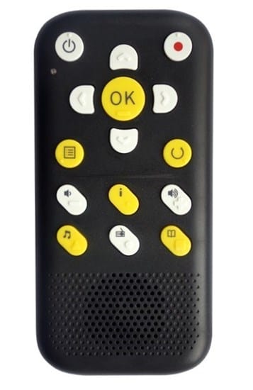 Na zdjęciu widoczne jest niewielkie, czarne, prostokątne urządzenie – przenośny odtwarzacz książek mówionych. Ma zaokrąglone krawędzie i duże, kontrastowe przyciski w kolorach żółtym i białym. W centralnej części znajduje się duży, okrągły przycisk „OK”, otoczony przyciskami kierunkowymi. Powyżej widoczny jest przycisk włączania oraz przycisk nagrywania oznaczony czerwonym kółkiem. Na urządzeniu znajdują się także przyciski z ikonami, m.in. menu, informacji, głośności, muzyki i książki. W dolnej części umieszczony jest głośnik. Urządzenie jest zaprojektowane z myślą o osobach niewidomych i słabowidzących, umożliwiając łatwą obsługę dotykową.